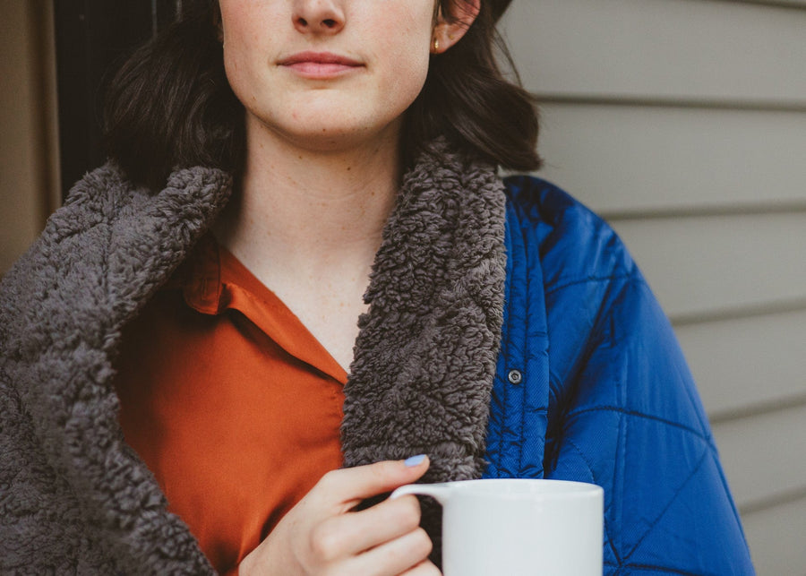 Close up of woman holding coffee and wrapped in a Kammok Blanket Mountain Blanket