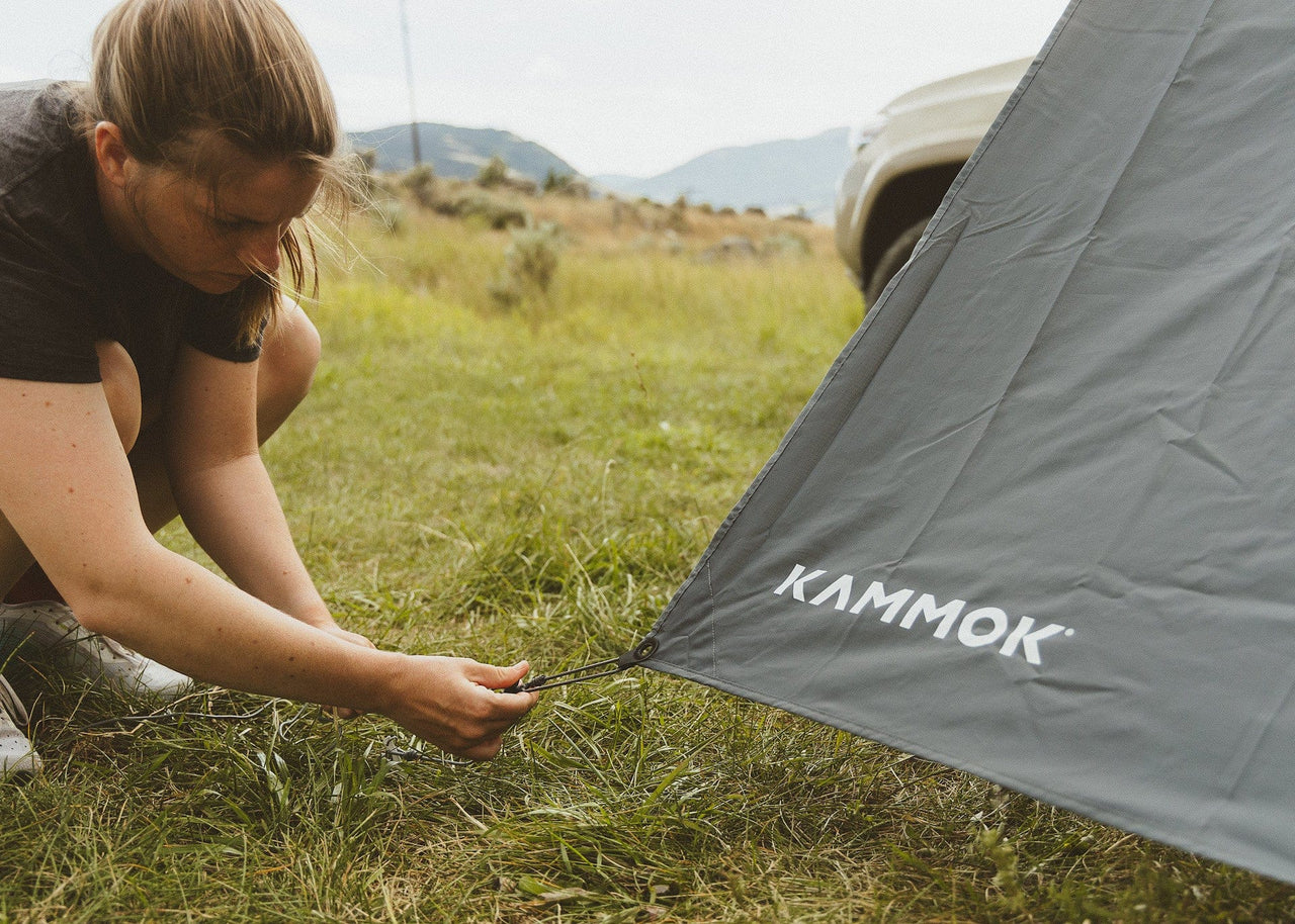 Women staking a Kammok Crosswing Shade Panel in the ground.