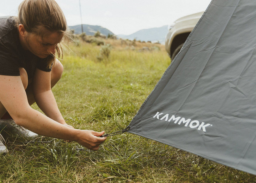 Women staking a Kammok Crosswing Shade Panel in the ground.
