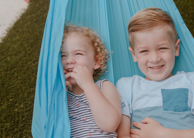 Cute kids smiling and snugging in a Kammok Hammock Roo Jr.