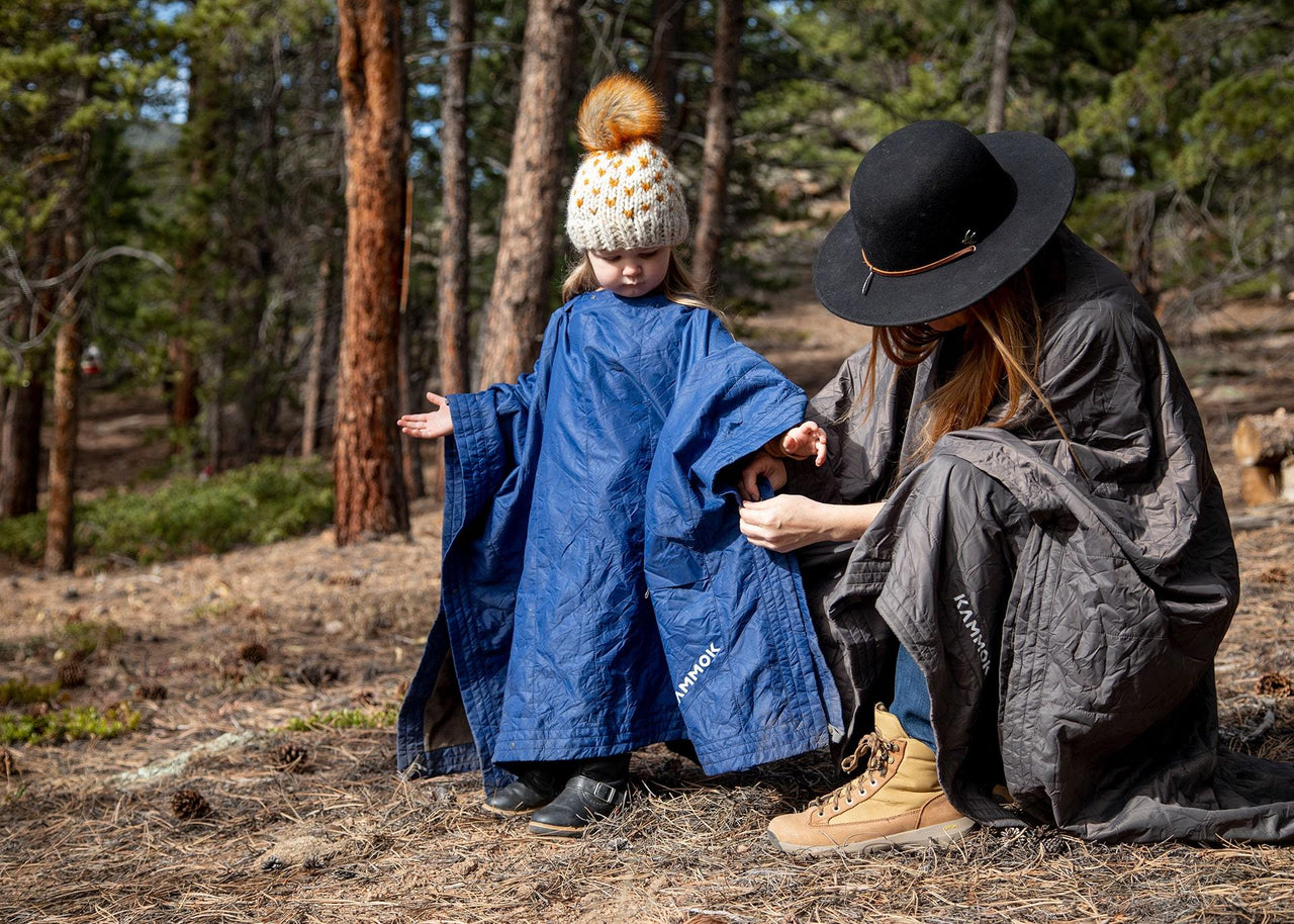 Mom and child wearing their Field Blankets in the woods.
