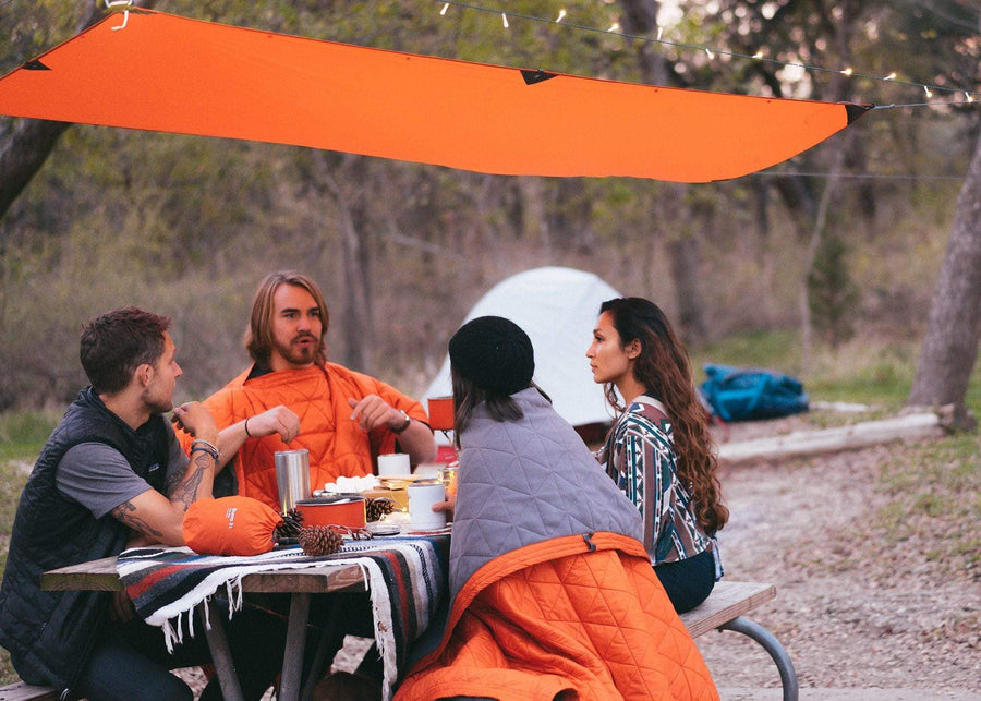 Friends sitting at a picnic table underneath Kammok Mesa Mat