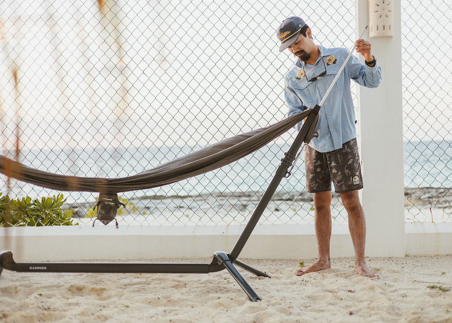 Man attaching Swiftlet Shade Poles to Swiftlet portable hammock stand.