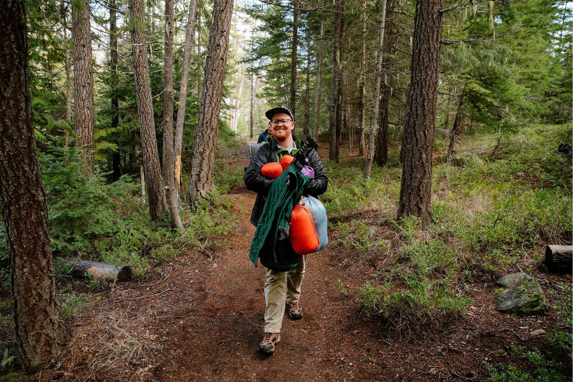 Man walking through woods with his Kammok gear in burro bags.