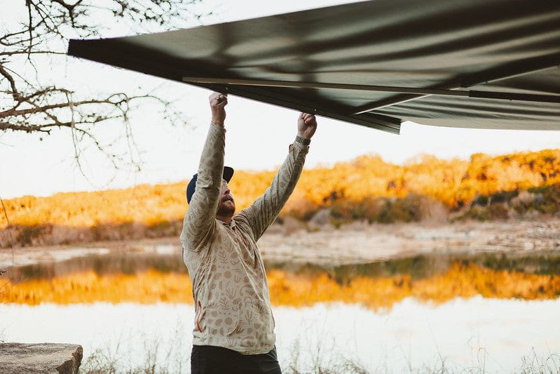 Man opening a Kammok Bundle Crosswing overlooking a lake and mountain.