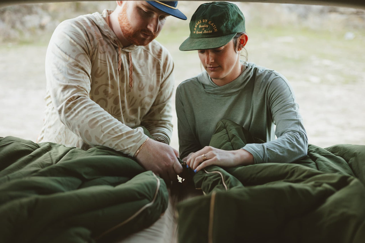 Two campters setting up their Kammok Ursa Sleep System to zip together.