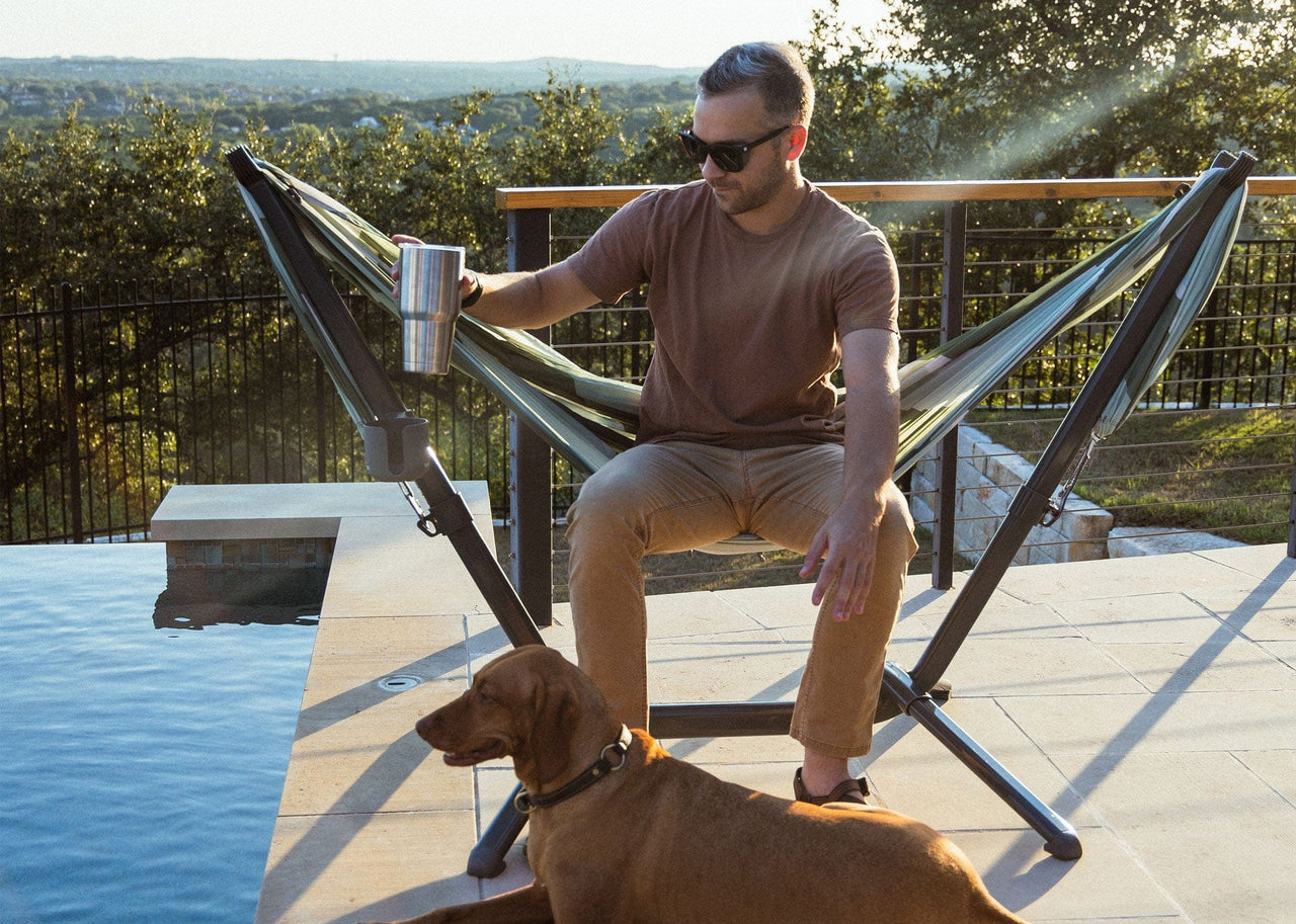 Man sitting in his swiflet next to the pool with dog lying next to him.