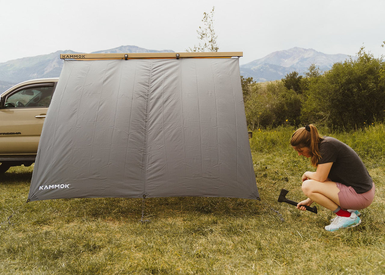 Kammok Crosswing Shade Bundle on truck with women hammering stakes for shade into ground.