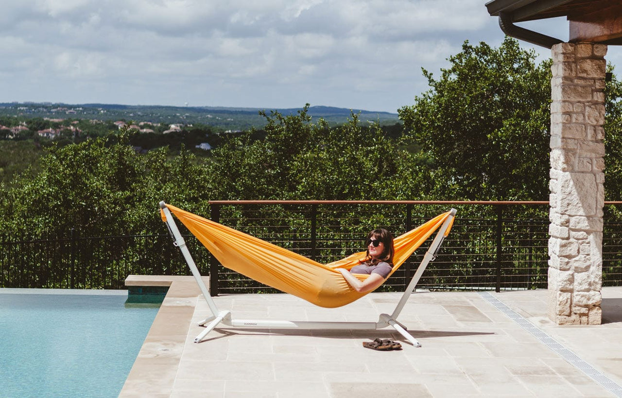 Woman lying by the pool in our Kammok Bundle Swiftlet Hammock Stand Bundle