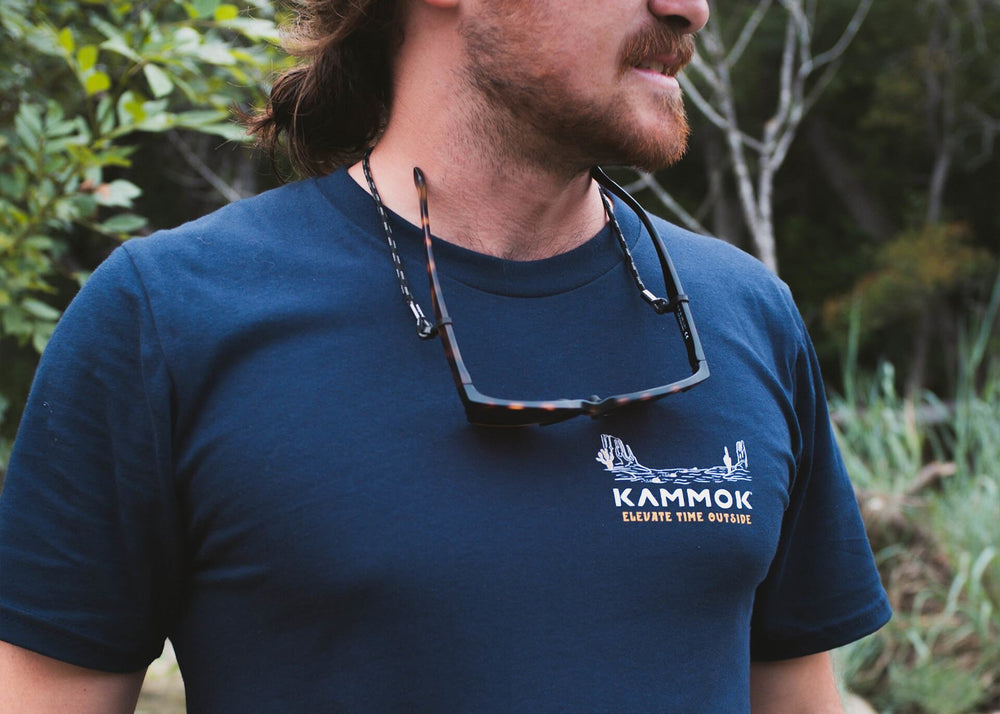 Man with beard and sunglasses around his neck wears a blue, Kammok Rock Skipping Companion tshirt. 