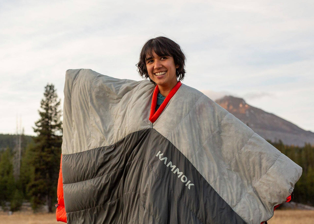 Girl in front of mountains with arms outstrestch in a Kammok Arctos 20 Quilt.