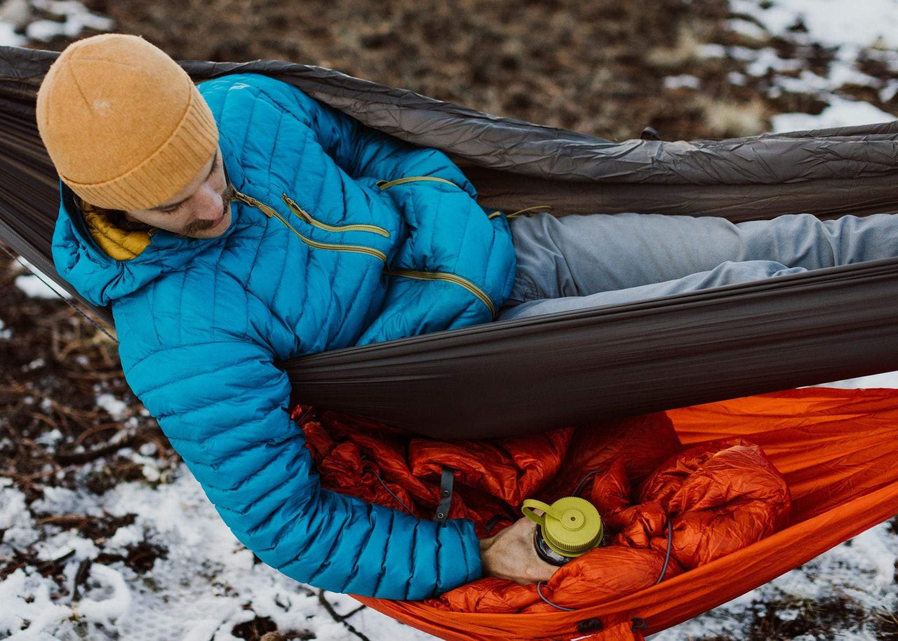 Man lying in hammock reaching into his Joey Gear Sling for a water bottle.