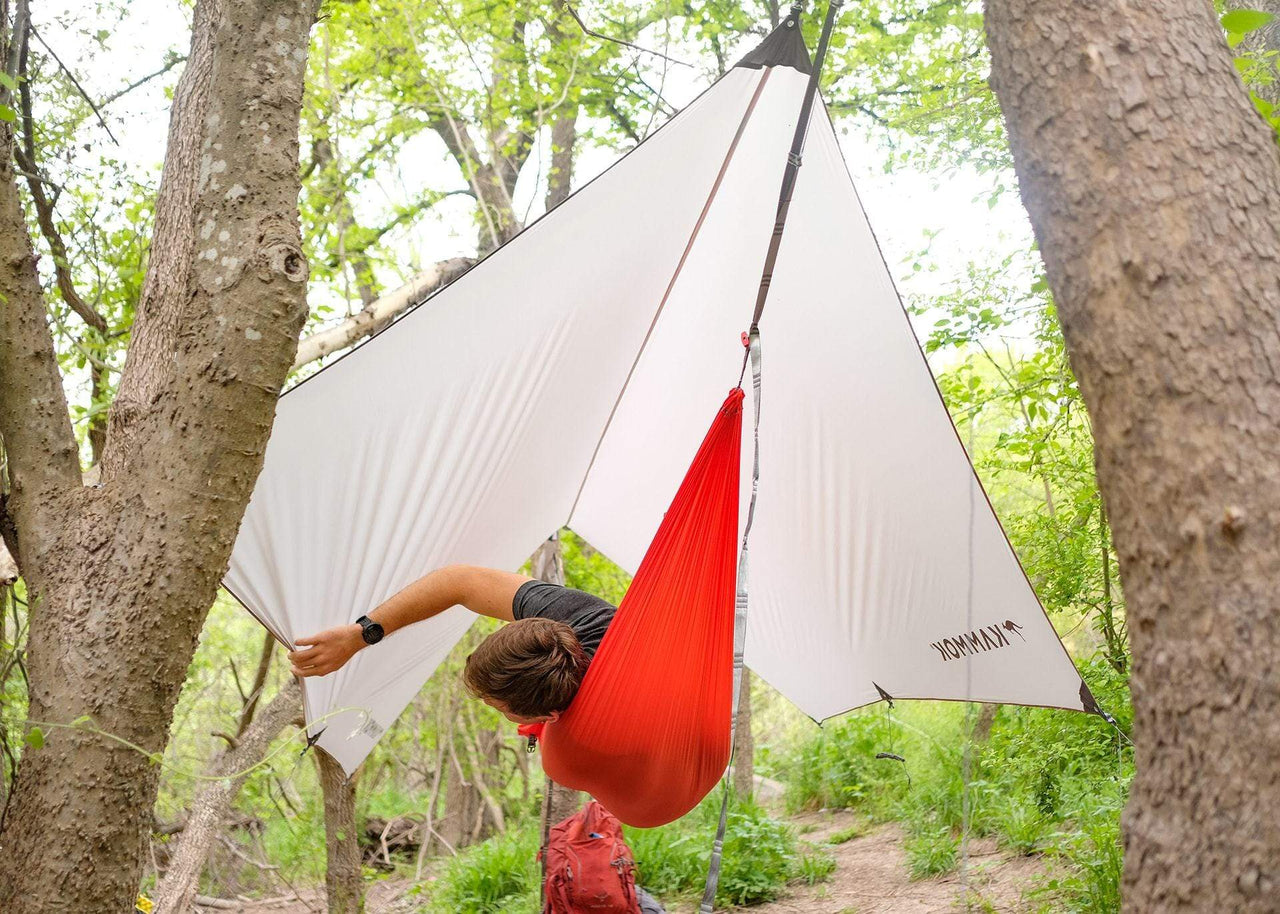 Mang hanging in hammock underneath a Kammok Weather Shelter Kuhli UL in woods.