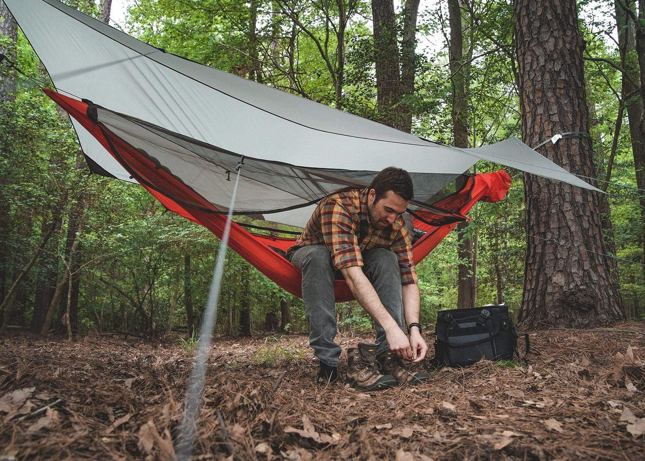 Man sitting in Mantis Tying shoes in woods.