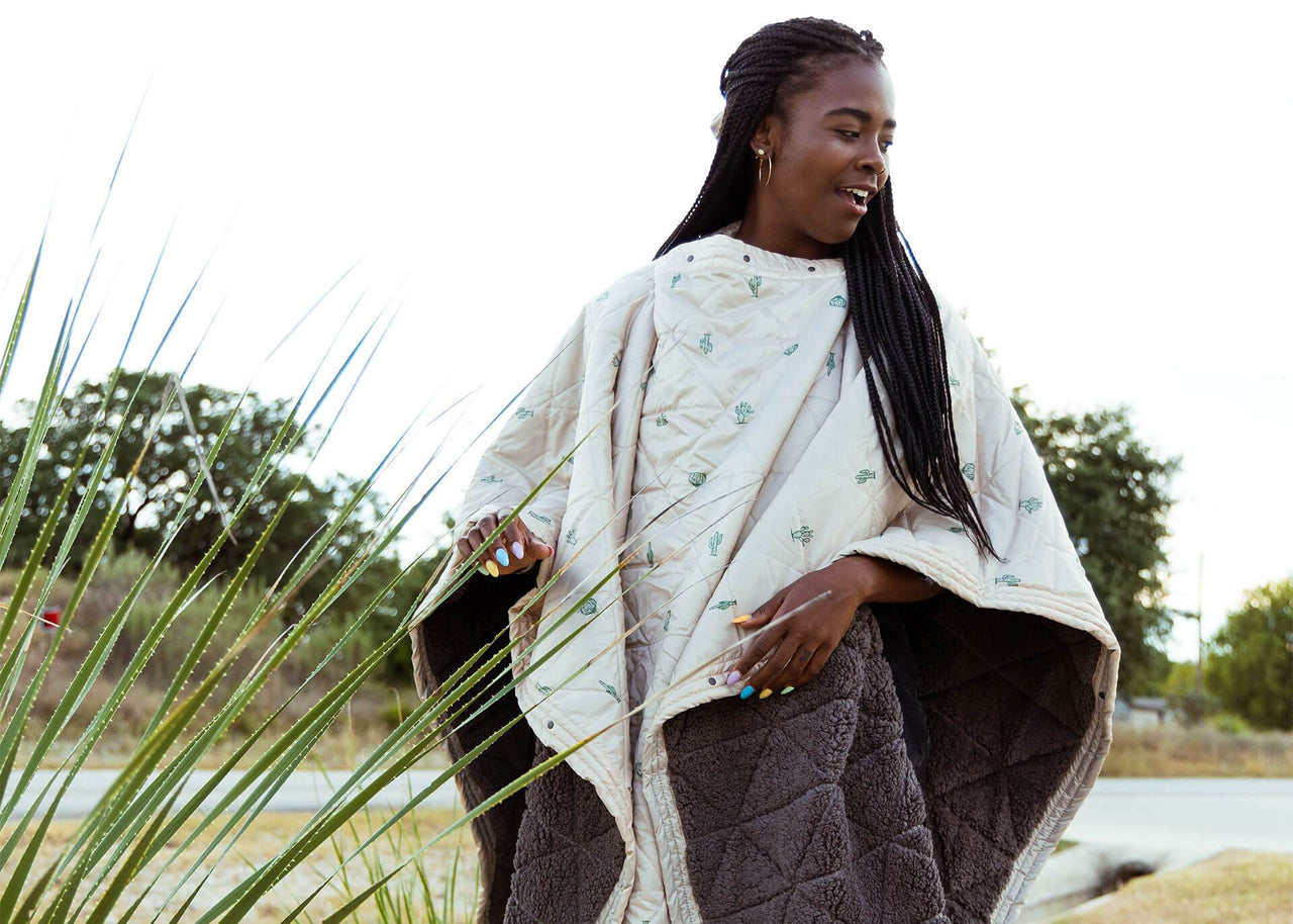 Girl wearing a Cacti Mountain Blanket next to a wild cactus with fleece underside showing.