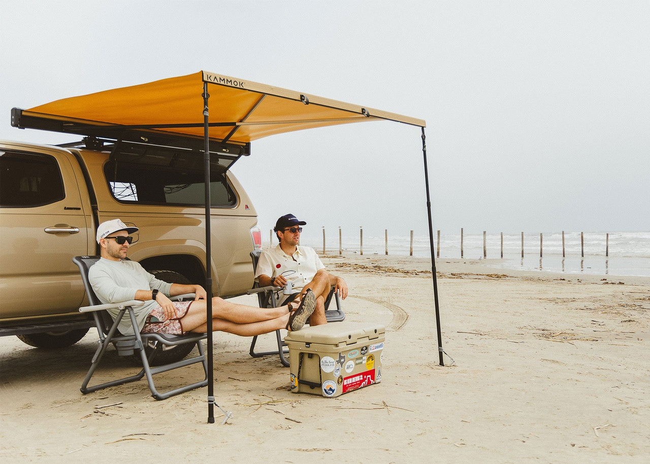 Two men sitting on beach under a Kammok Crowwsing with Pole Pack installed.