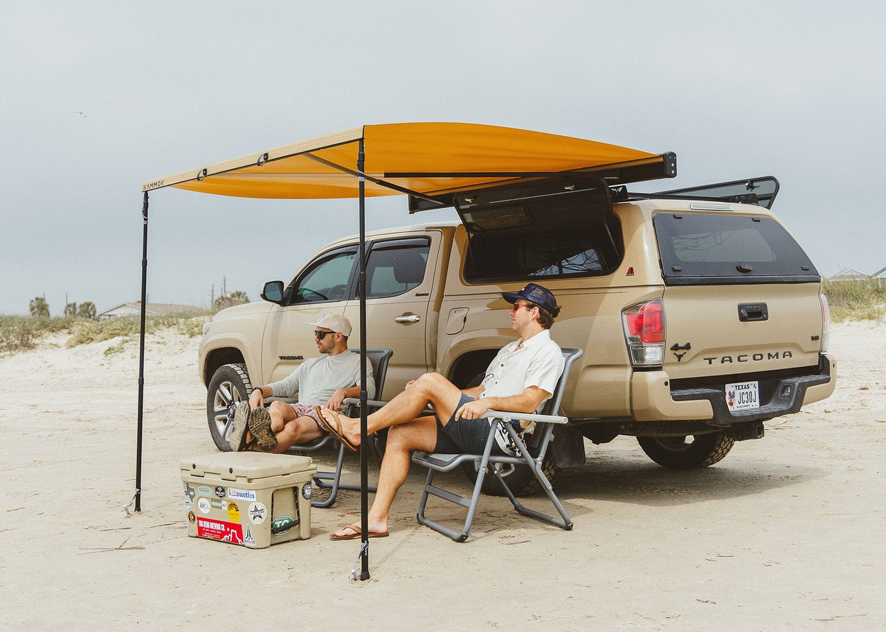 Two guys sitting undreneath a Kammok Crosswing on a Toyota Tacoma with a Pole Pack installed.