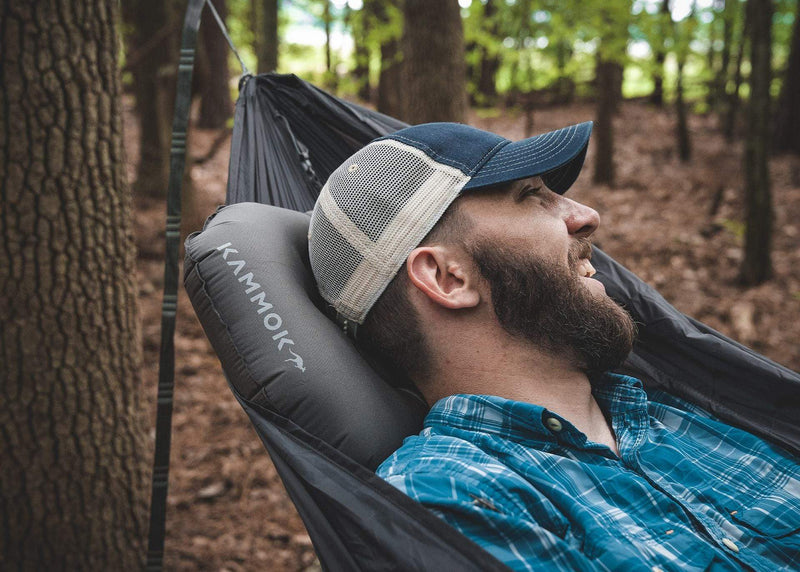 Man lying in Roo Hammock with on a puffin pillow in woods.