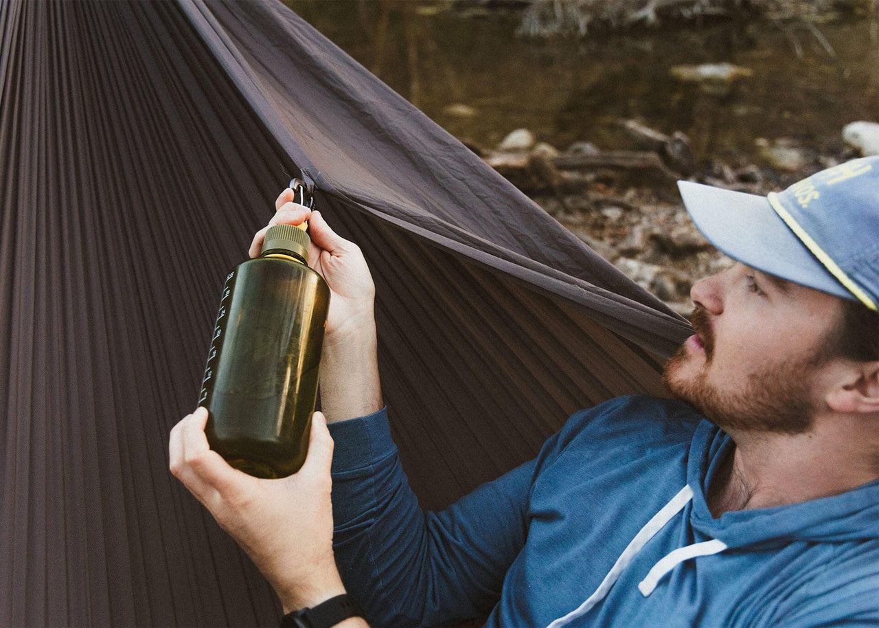 Man conecting a water bottle to a Kammok Hammock Roo Double XL Granite Gray