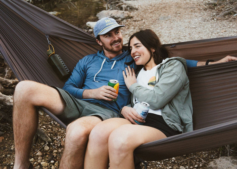 Couple sitting outside drinking beer on a Kammok Hammock Roo Double XL Granite Gray
