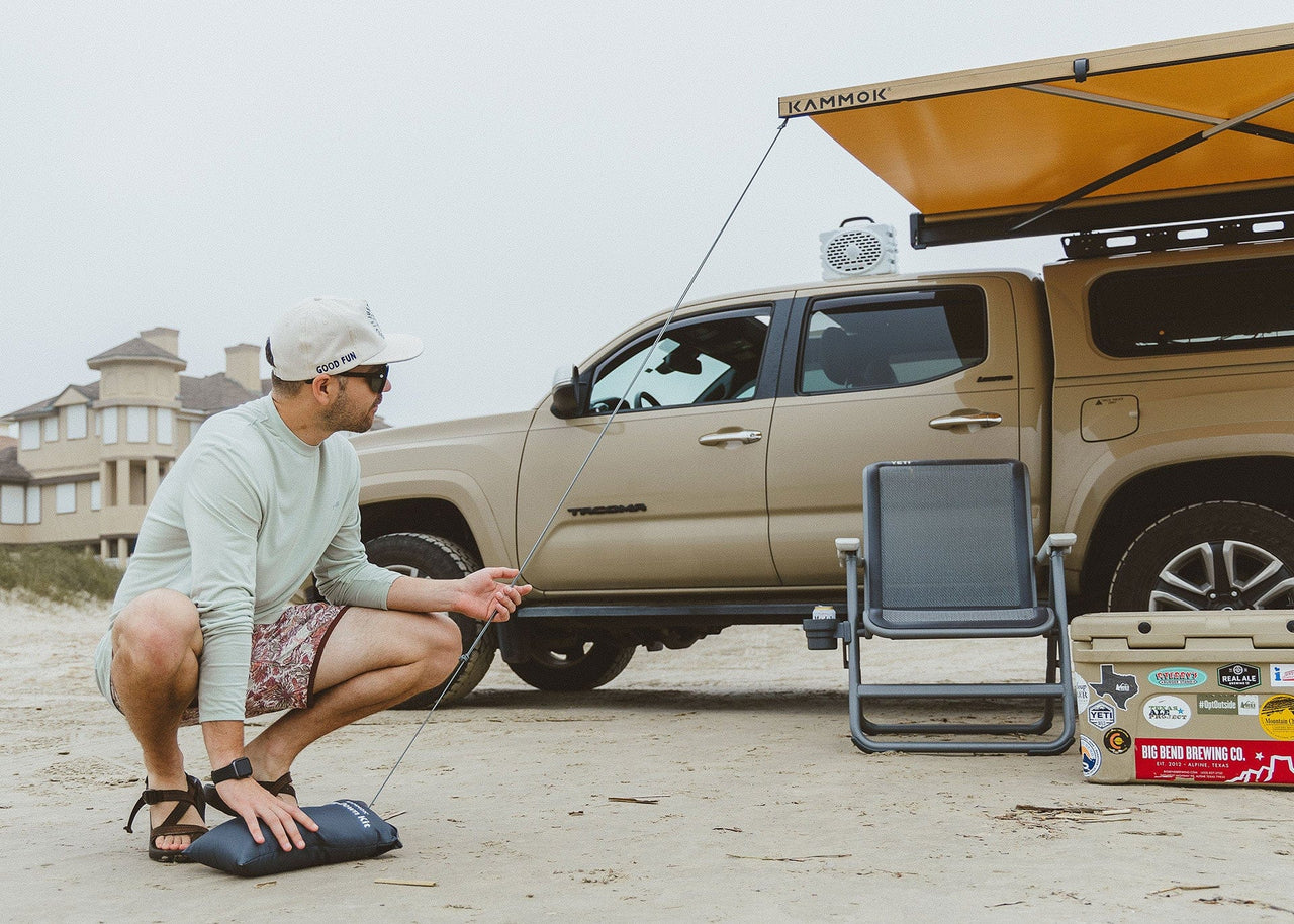 Man on the beach installing his Kammok Crosswing Tie-Down Kit.