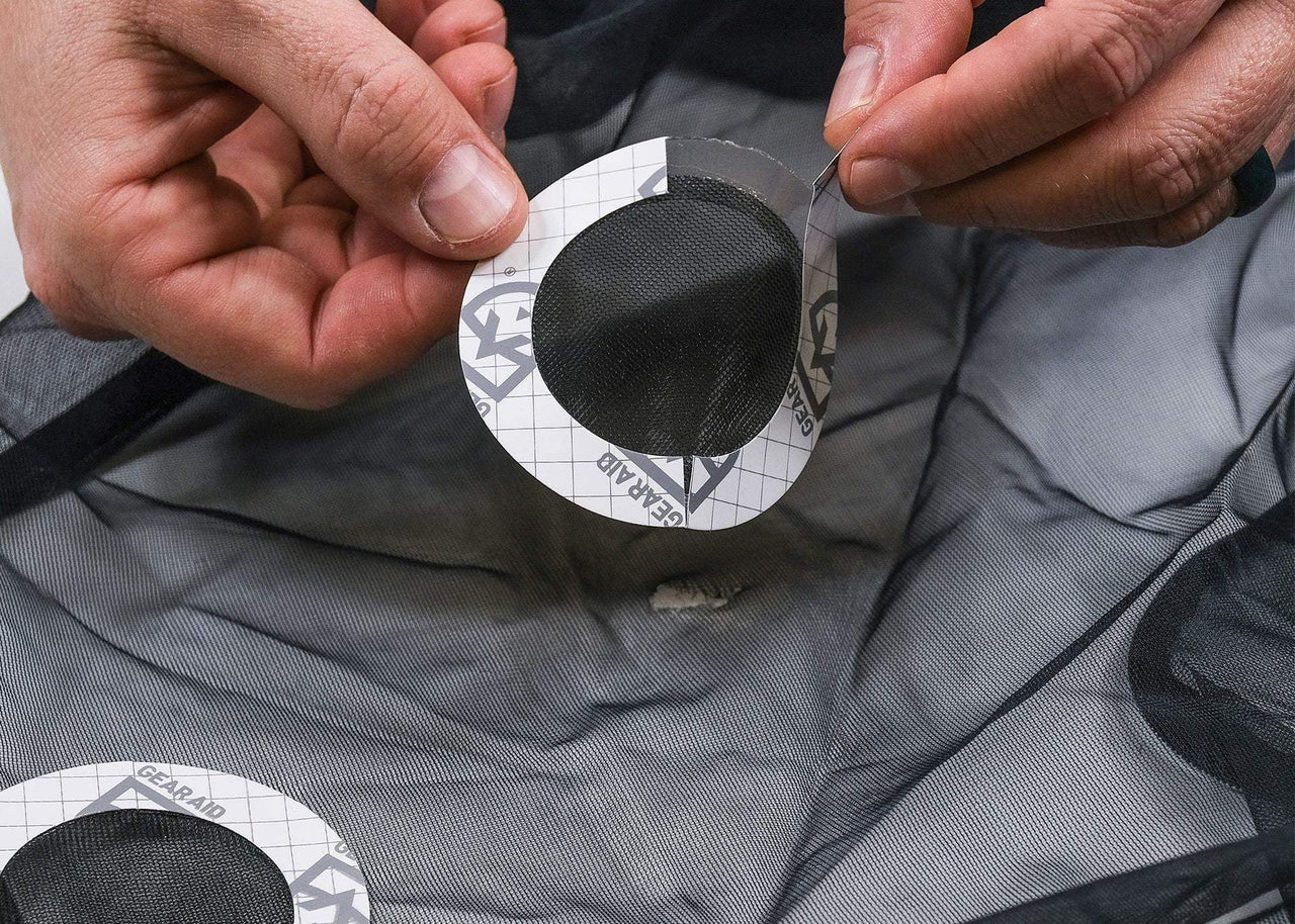 Close up of man's hands applying a Kammok Gear Aid Tenacious Tape Mesh Patches