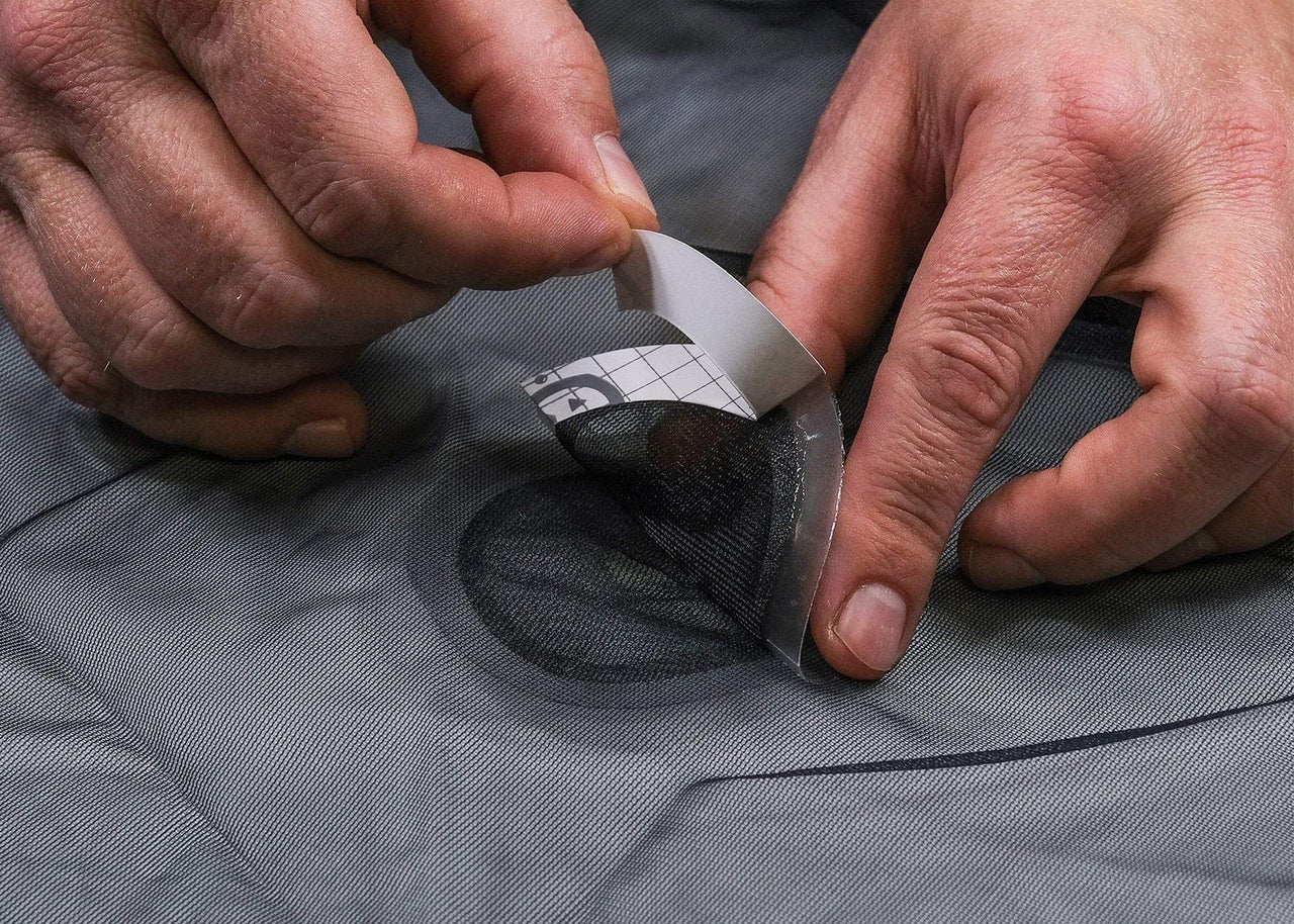 Close up of man's hands applying a Kammok Gear Aid Tenacious Tape Mesh Patches