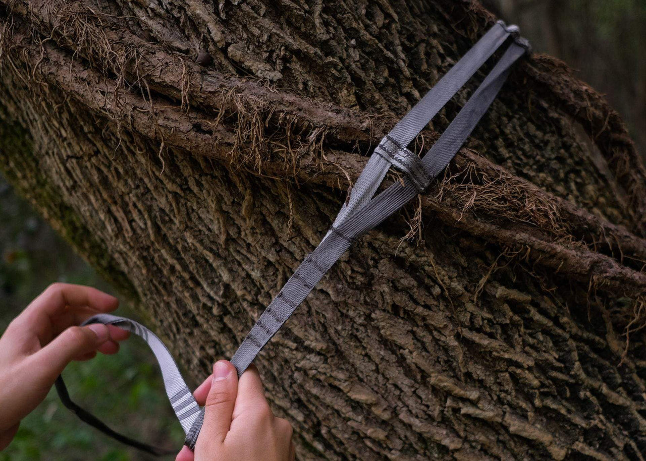 Close up of hands wrapping Kammok python straps around tree.