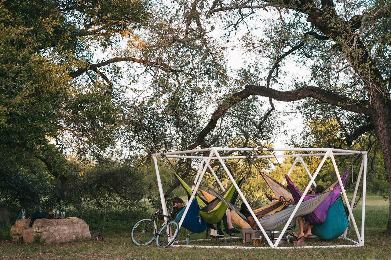 Kammok Stand Weaver on a campground with people hanging together in hammocks.